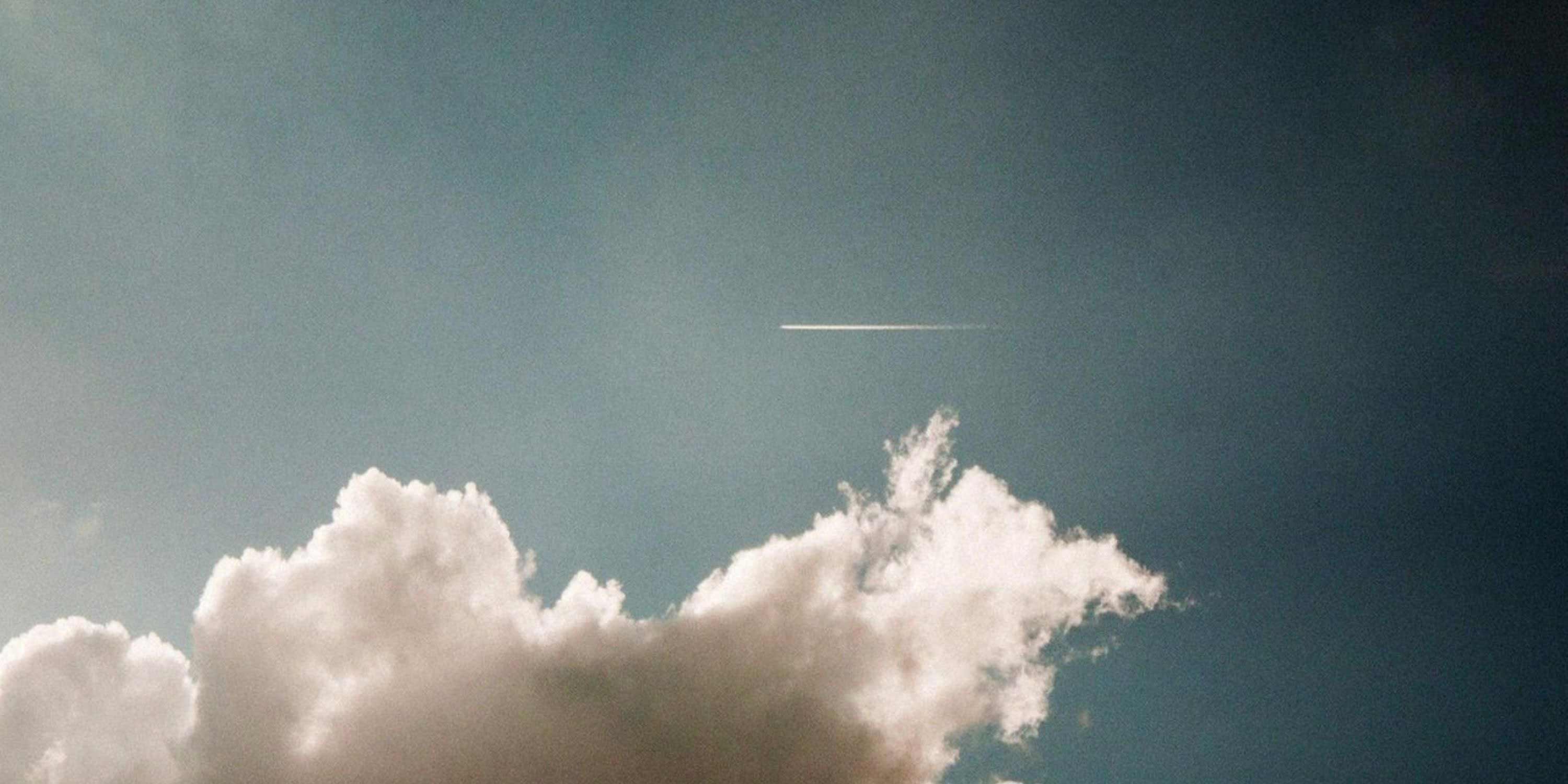 Photo of clouds and an airplane contrail